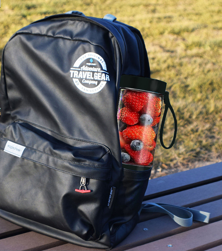 Black backpack with 'Travel Gear' branding on a wooden surface with a blurred natural background