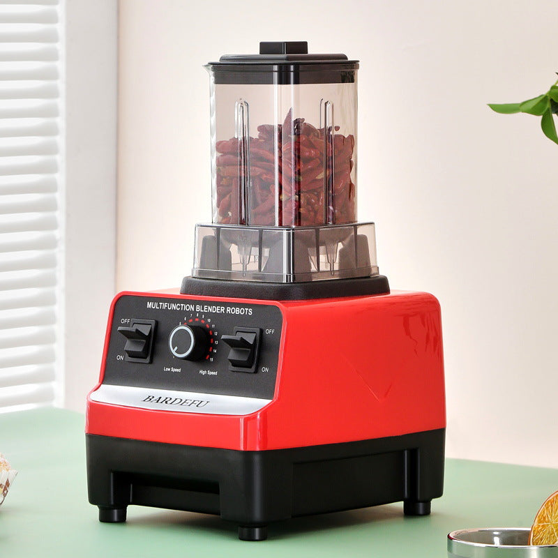 Red and black blender with ingredients inside on a light green surface.