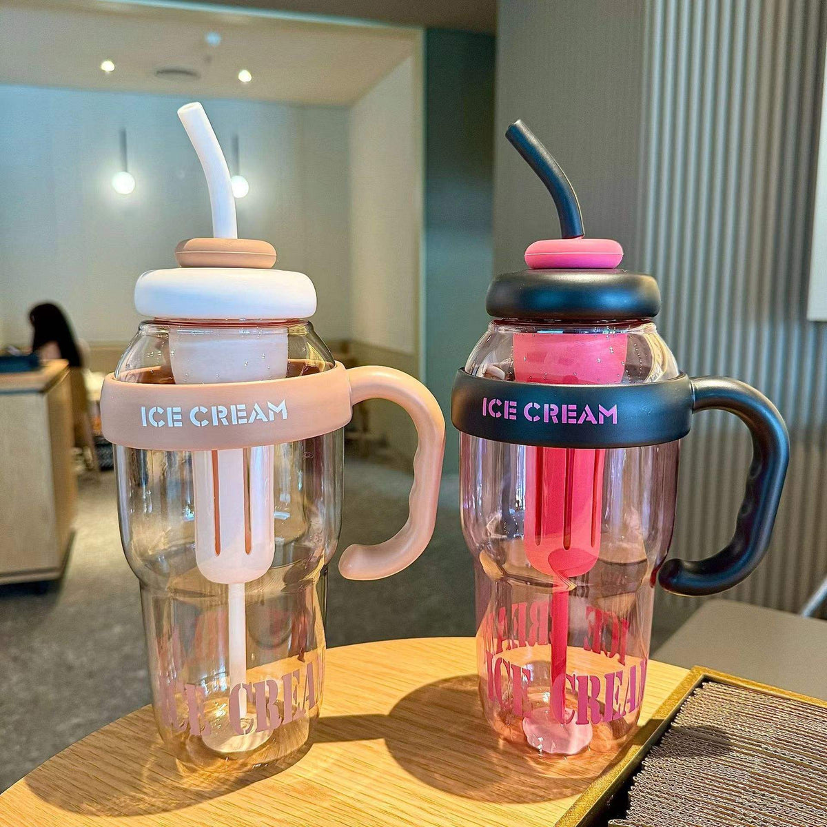 Two transparent cups with pink and blue handles and 'ICE CREAM' text on a wooden surface.
